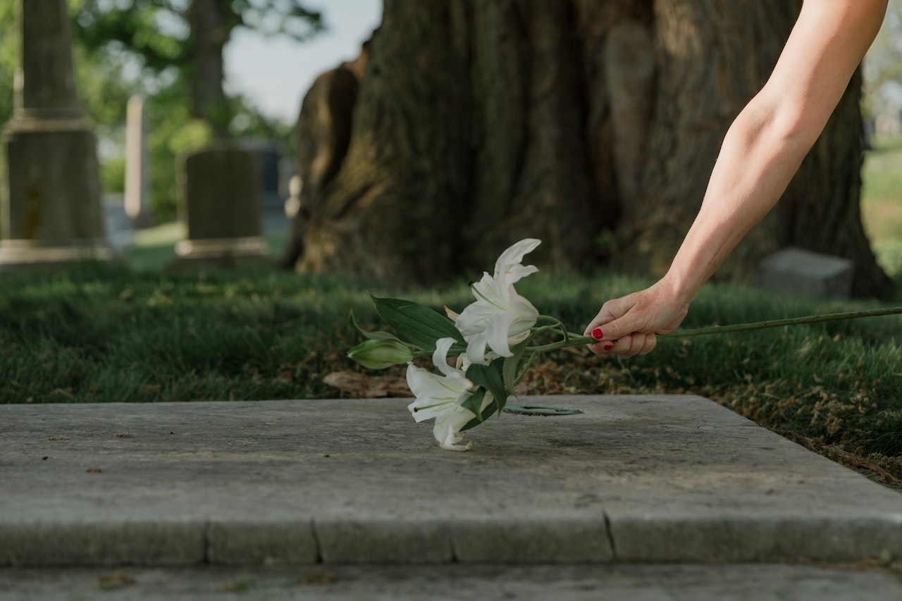 Person putting flowers on a grave