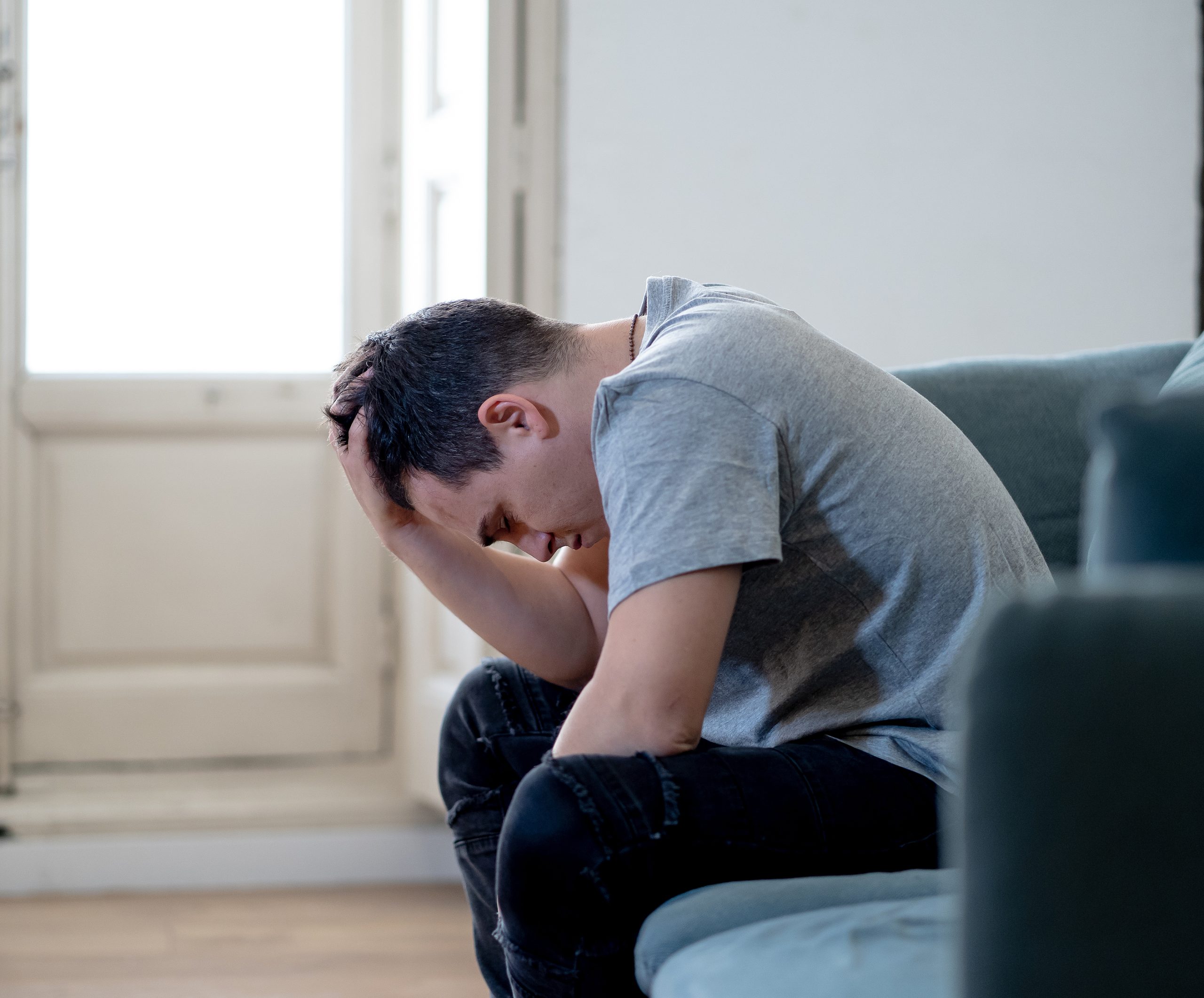 man on couch with his hands in his head, very discouraged