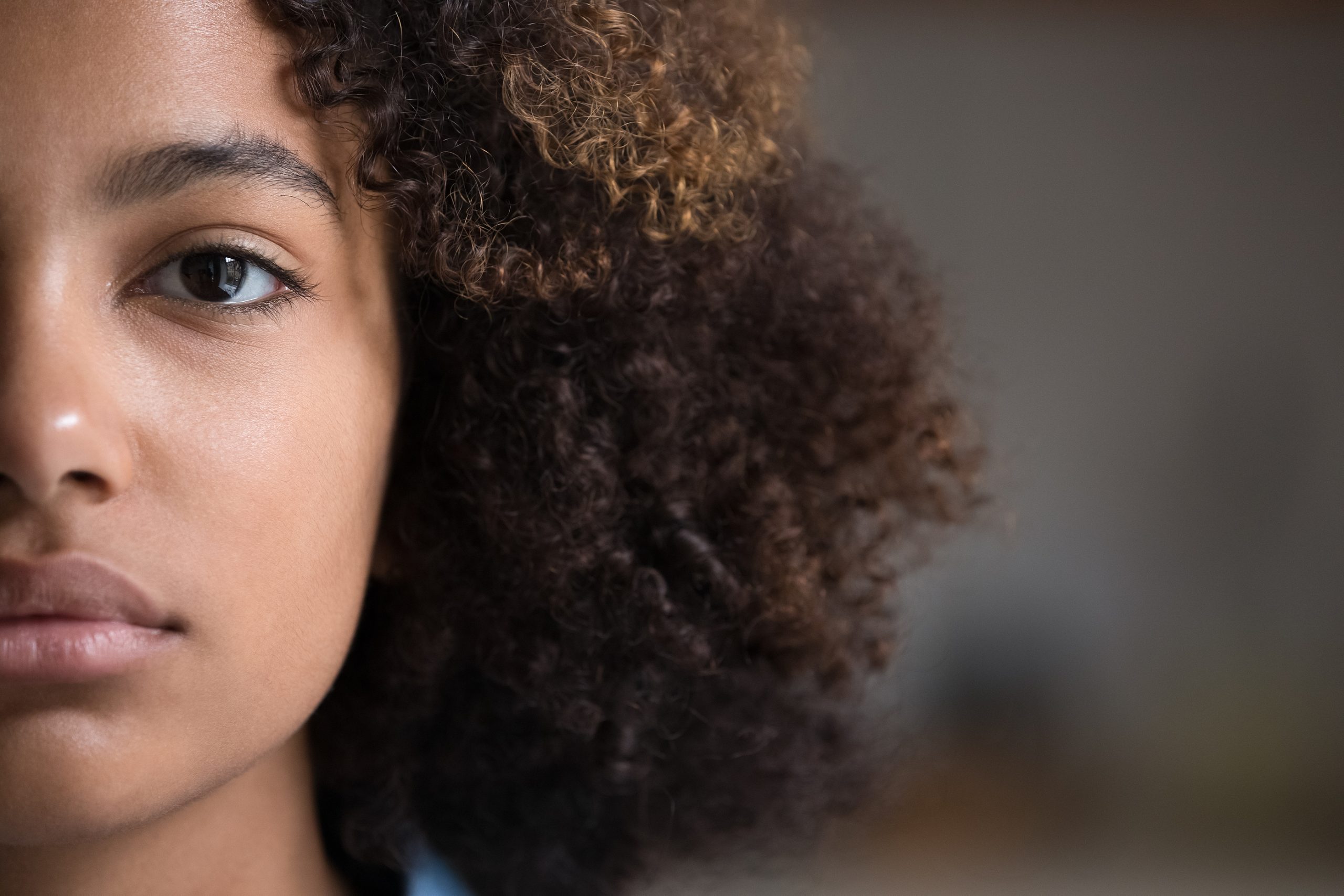 Half of young girls face, looking forward, sad