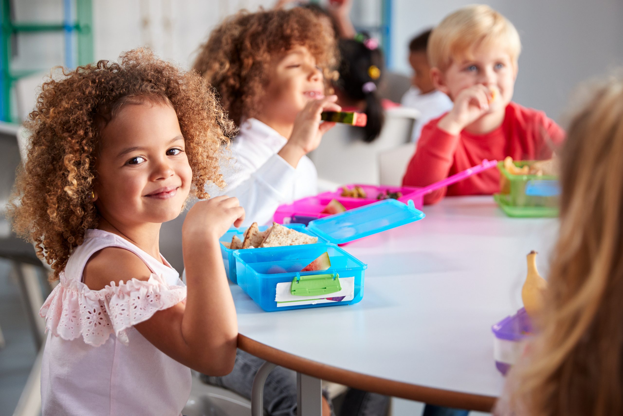 Confident little girl at table with peers.