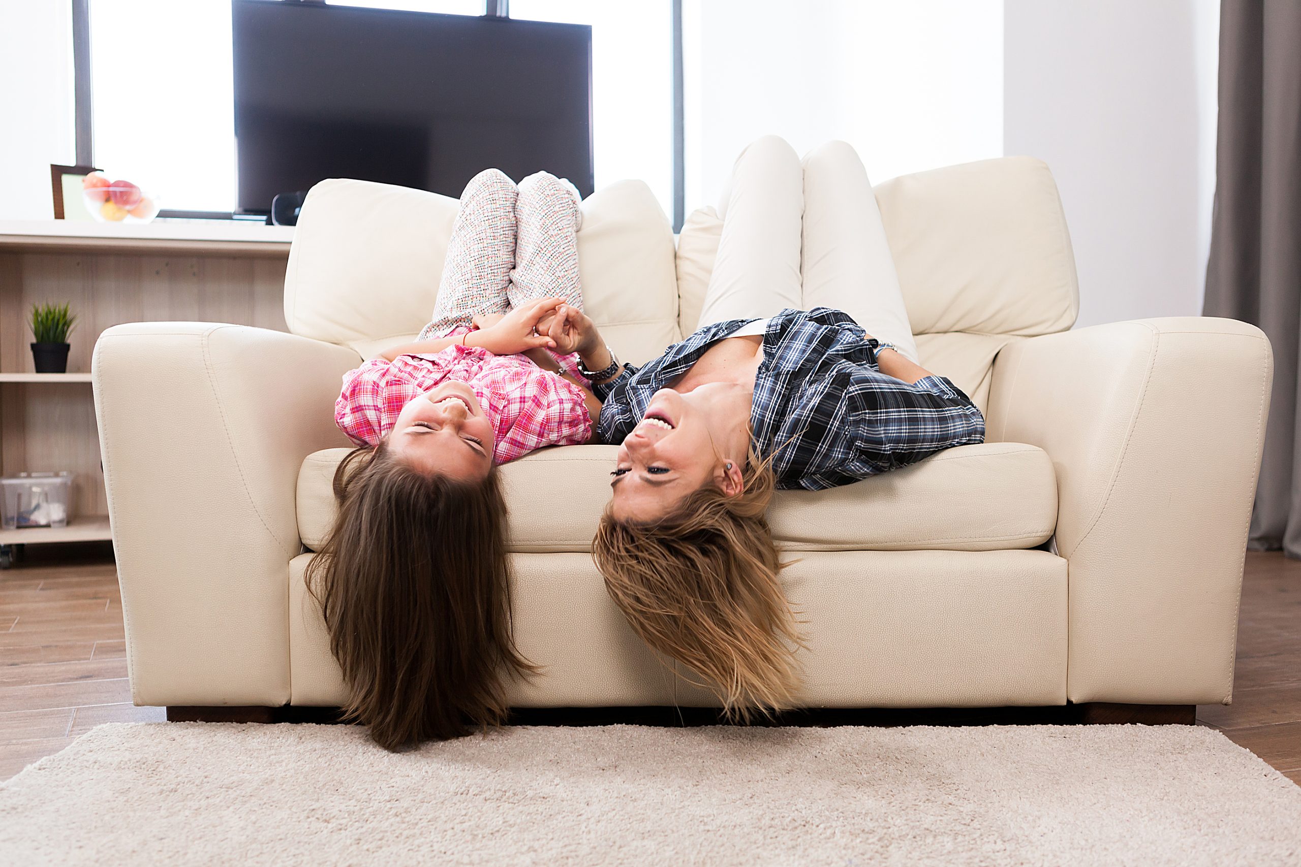 Mom lying on couch with daughter laughing together.