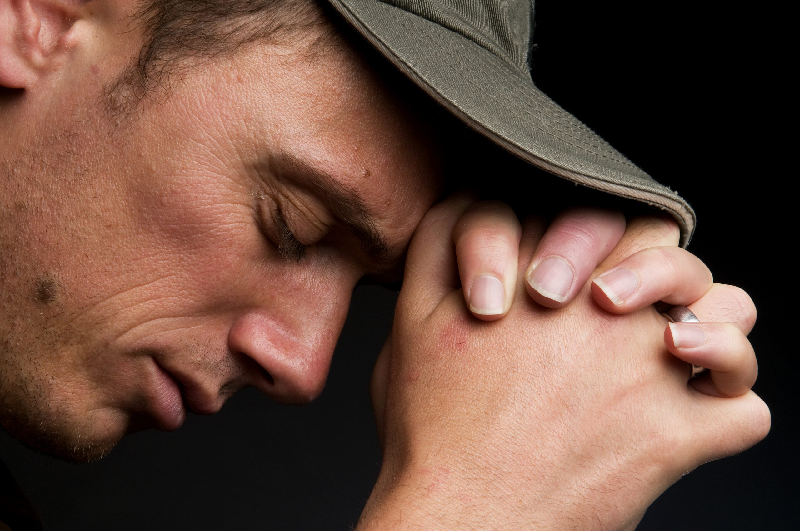 Man with hat, hands folded, praying