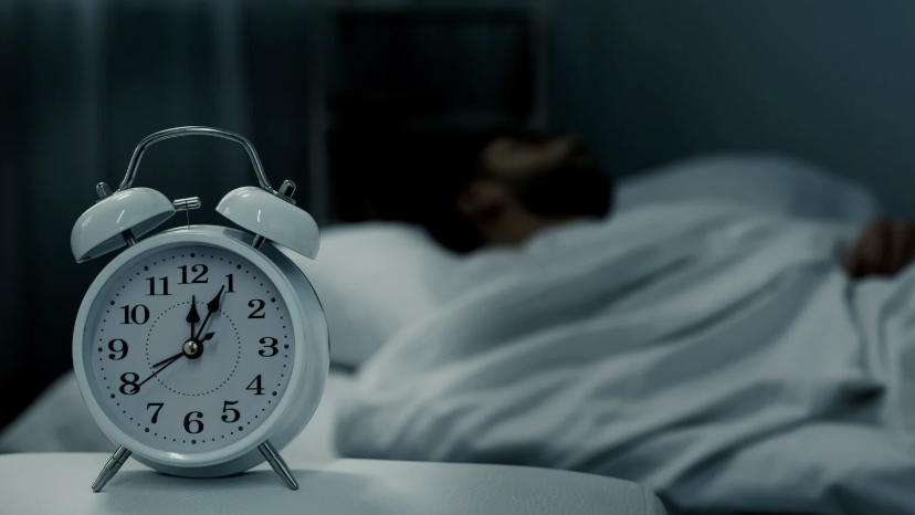 alarm clock with a sleeping man in the background