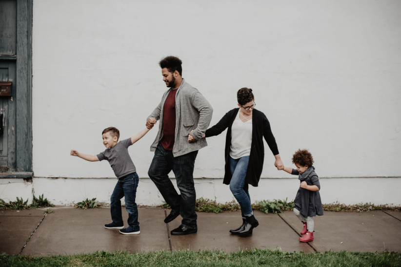 Mother and father walking and holding hands with small children