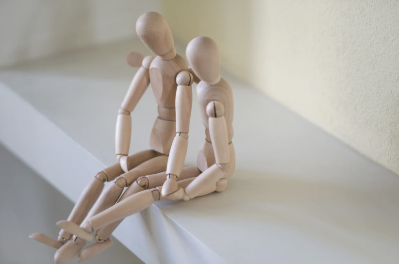 two wooden mannequin dolls sitting together