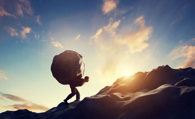 man carrying a boulder up a rocky mountain