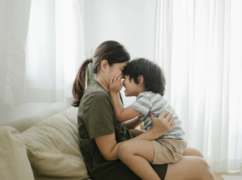 son sitting in mother's lap facing her on the couch