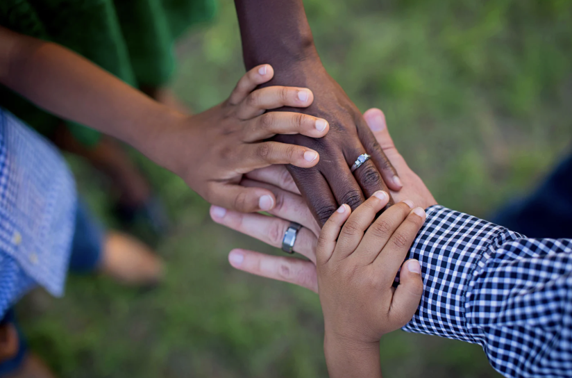 father, mother, child putting hands together