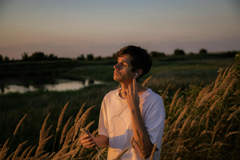 man listening to music at sunset in a field