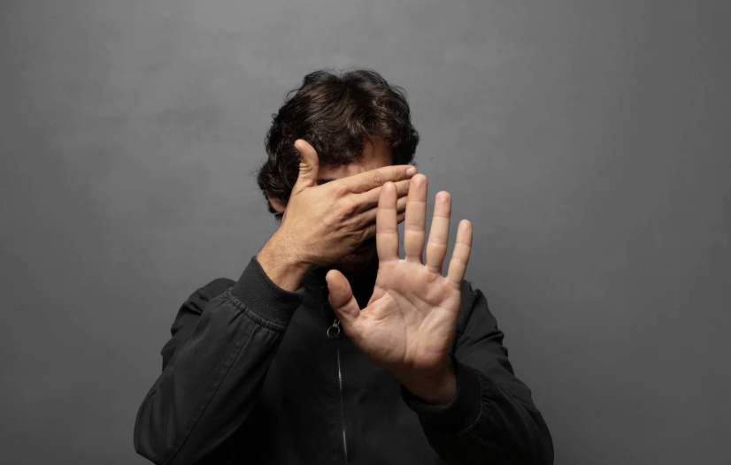 Man covering his eyes and putting out hand